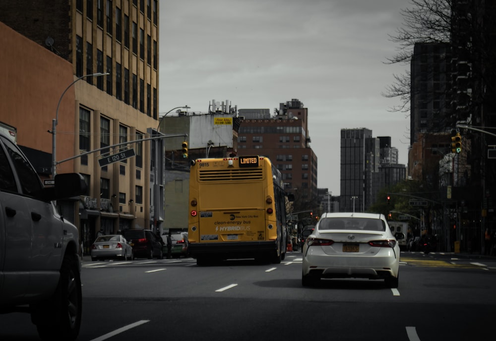 a yellow bus driving down a street next to tall buildings