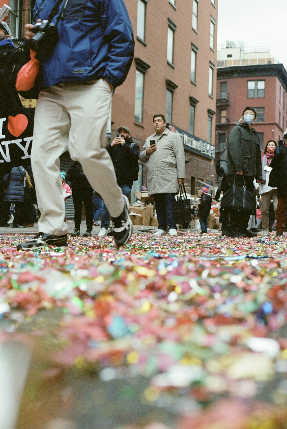 a group of people standing on a street next to a pile of confetti