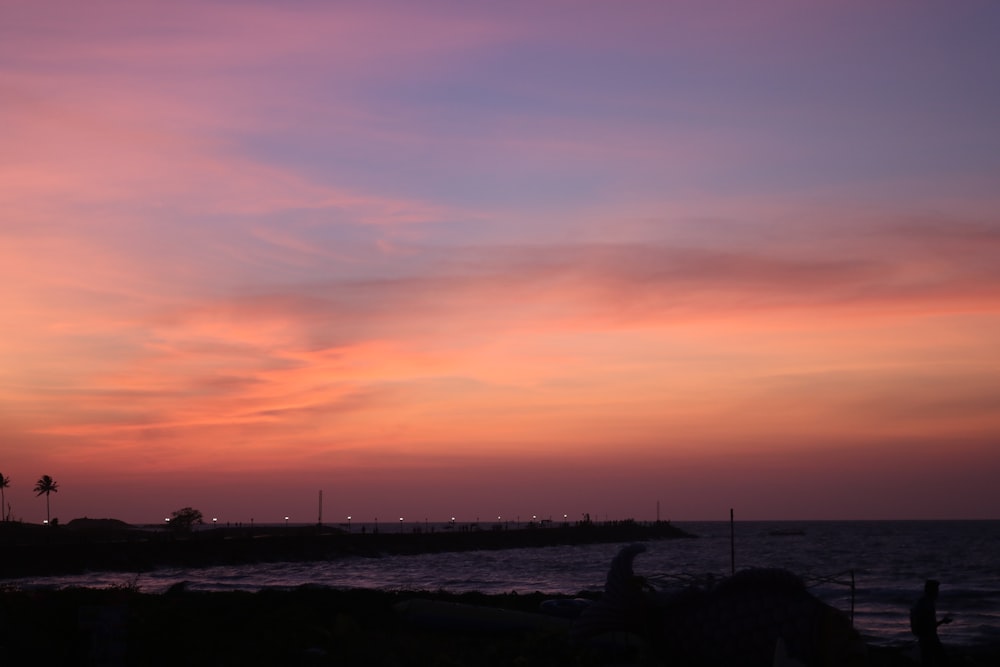 a sunset over a body of water with palm trees