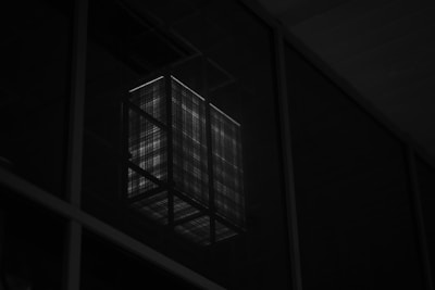 Close-up of a minimalist geometric light fixture casting precise beams in a dark room.