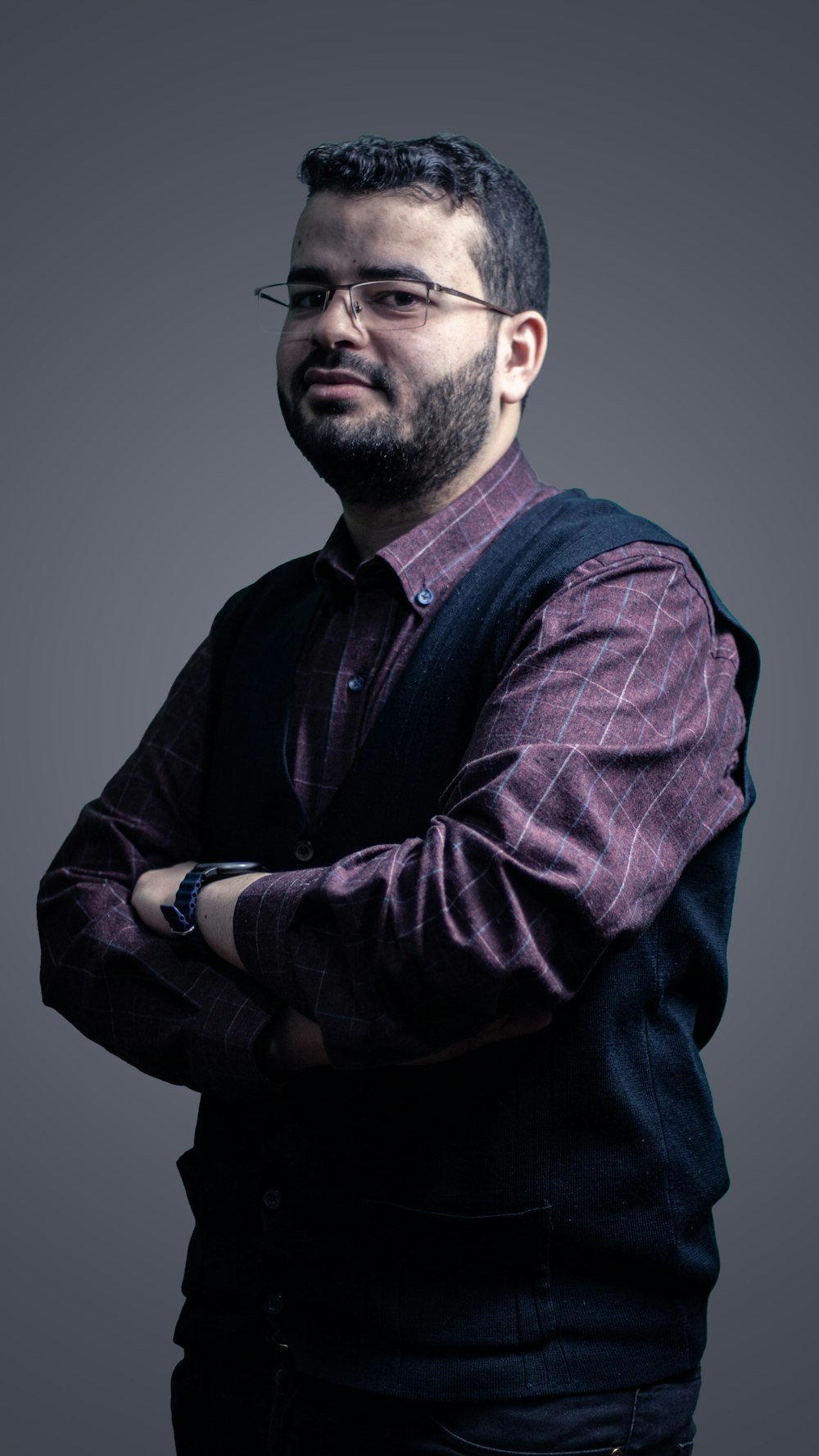 a man with a beard and glasses standing with his arms crossed