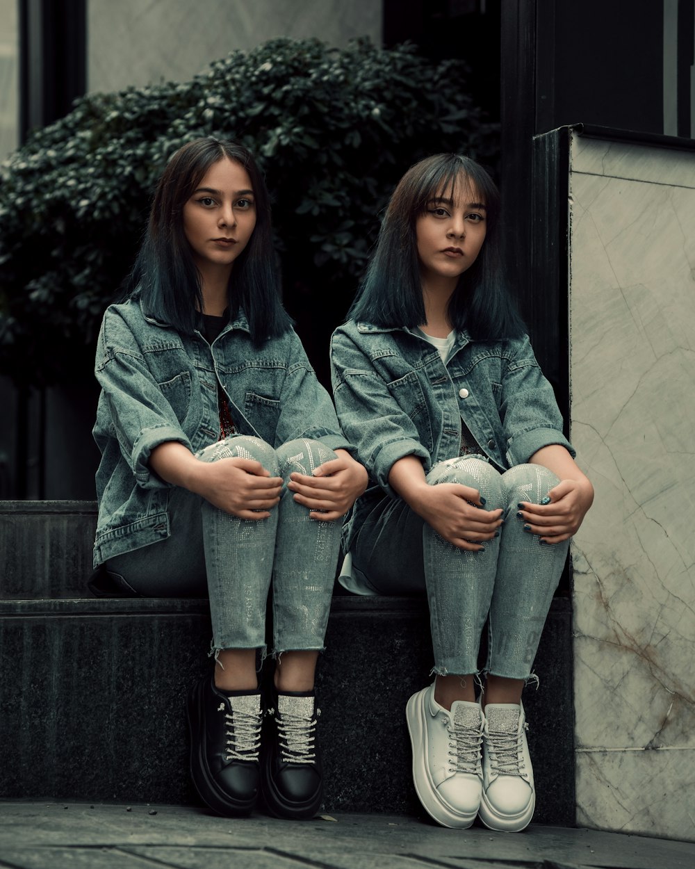 two young women sitting on the steps of a building
