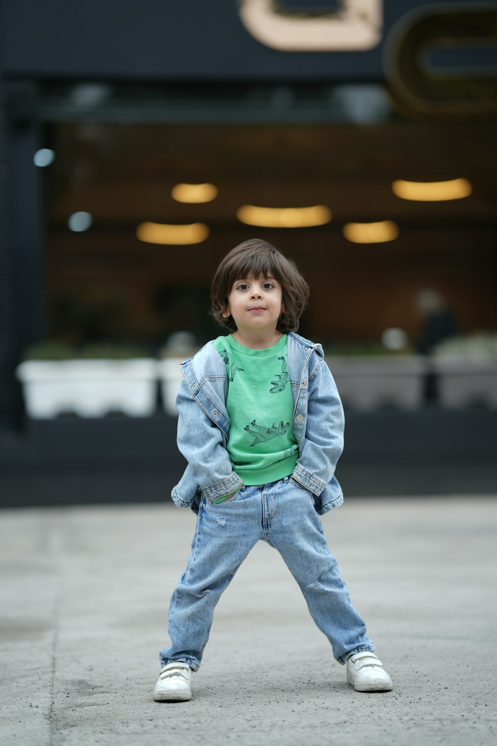 a young boy standing on a sidewalk in front of a building