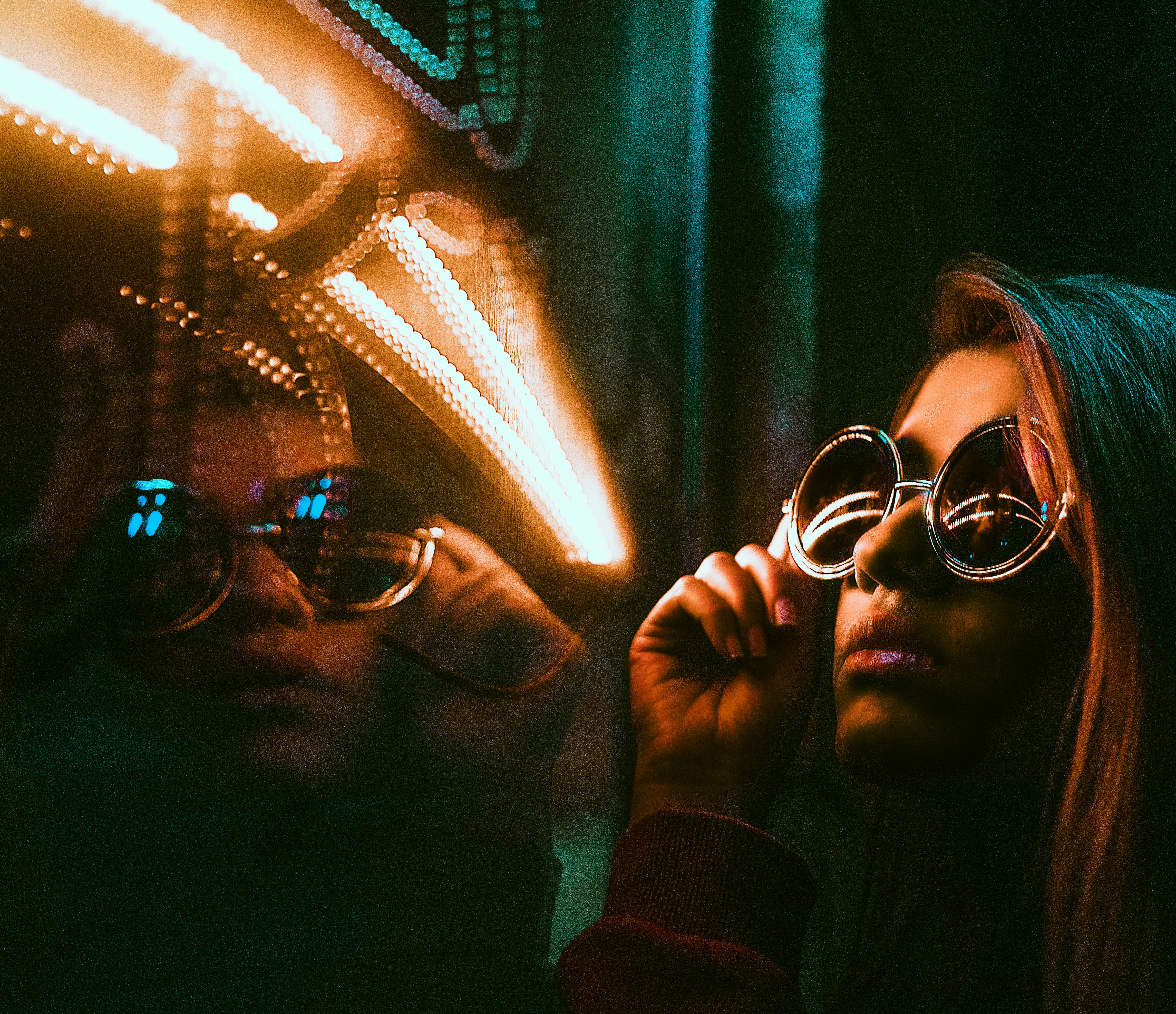 a woman in glasses looking at herself in a mirror
