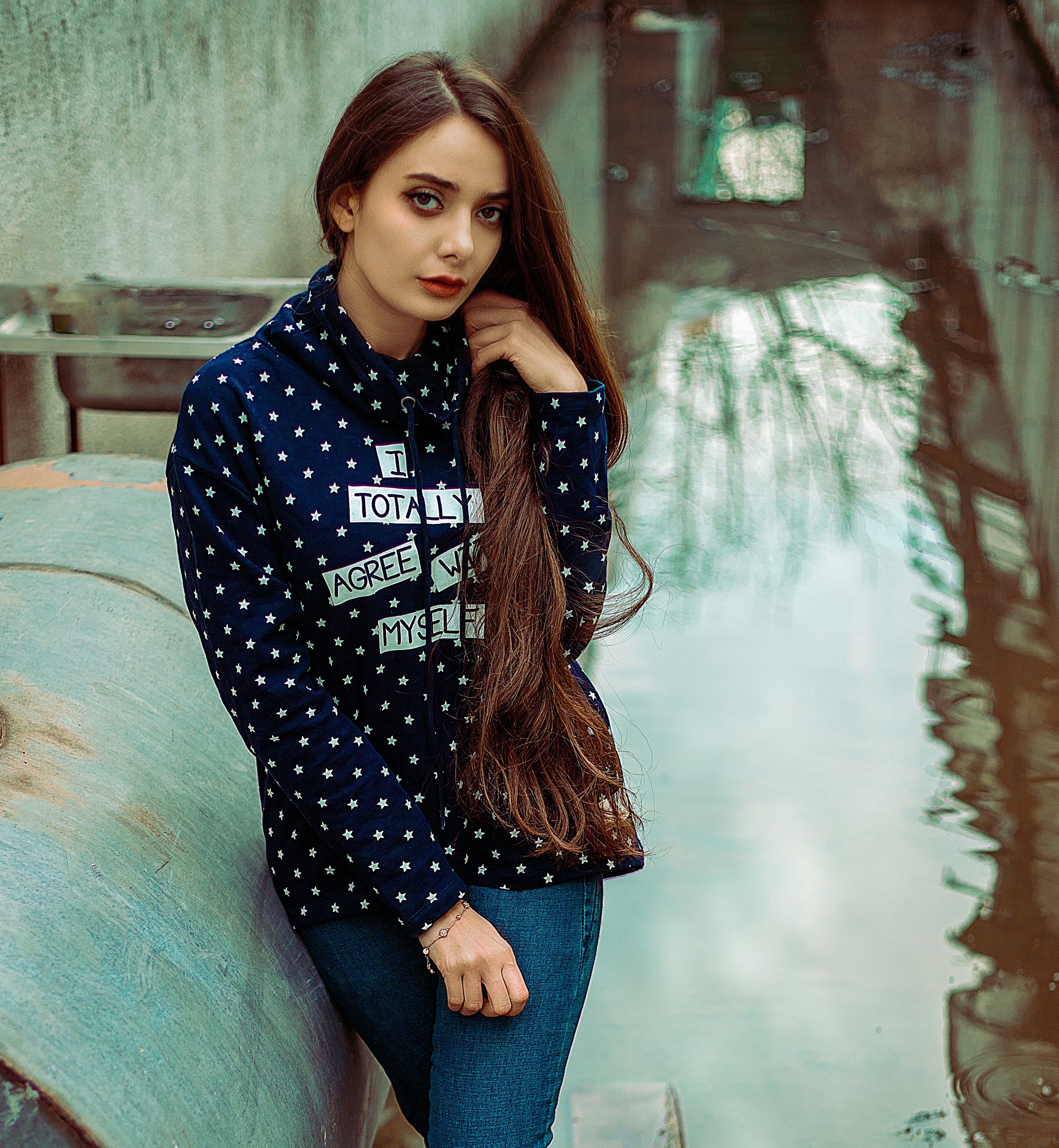 a woman with long hair leaning against a wall