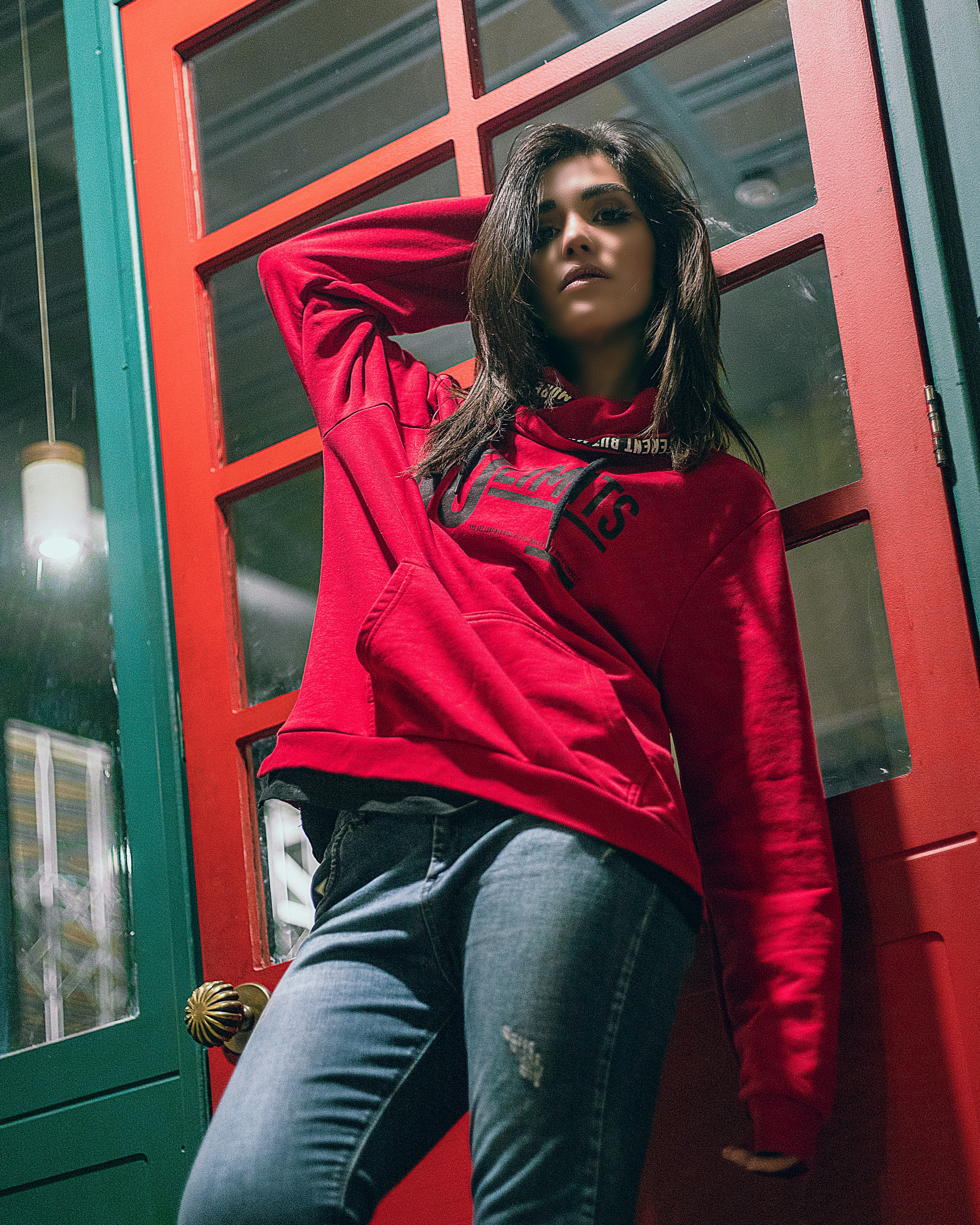 a woman in a red shirt leaning against a red door