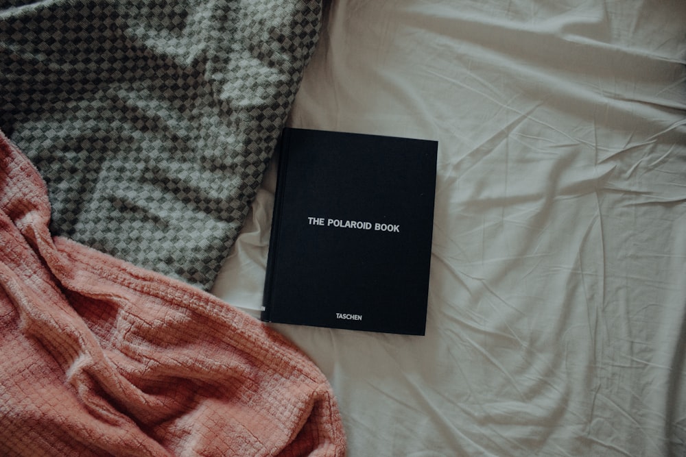 a book laying on top of a bed next to a blanket