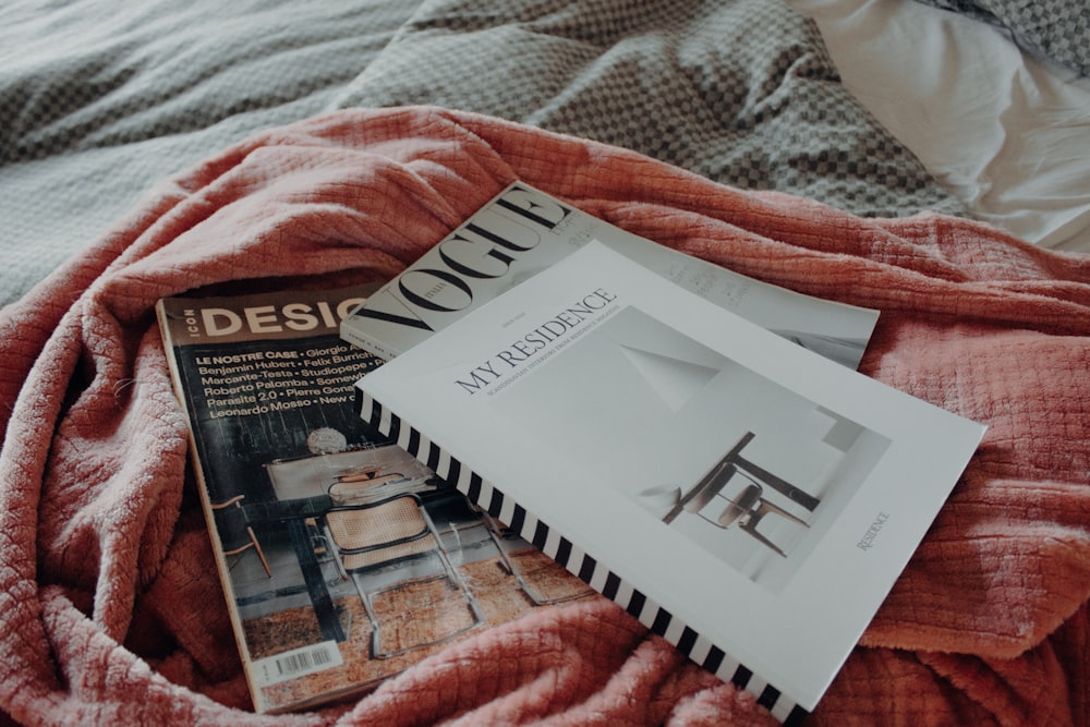 a bed with a red blanket and a book on top of it