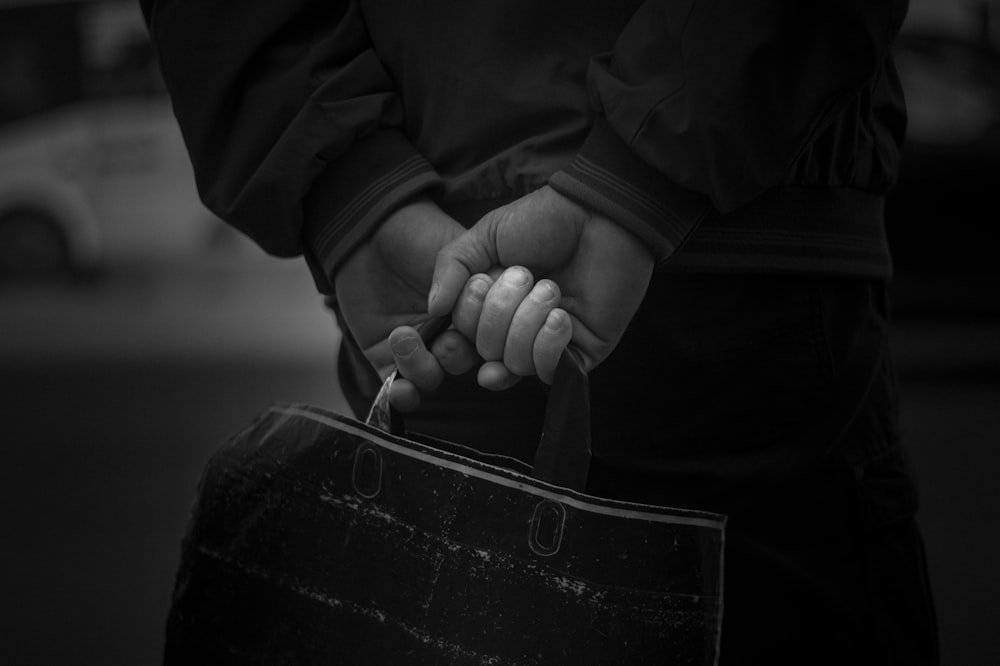 a black and white photo of a person holding a handbag