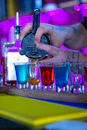 a bartender pours a drink into shot glasses