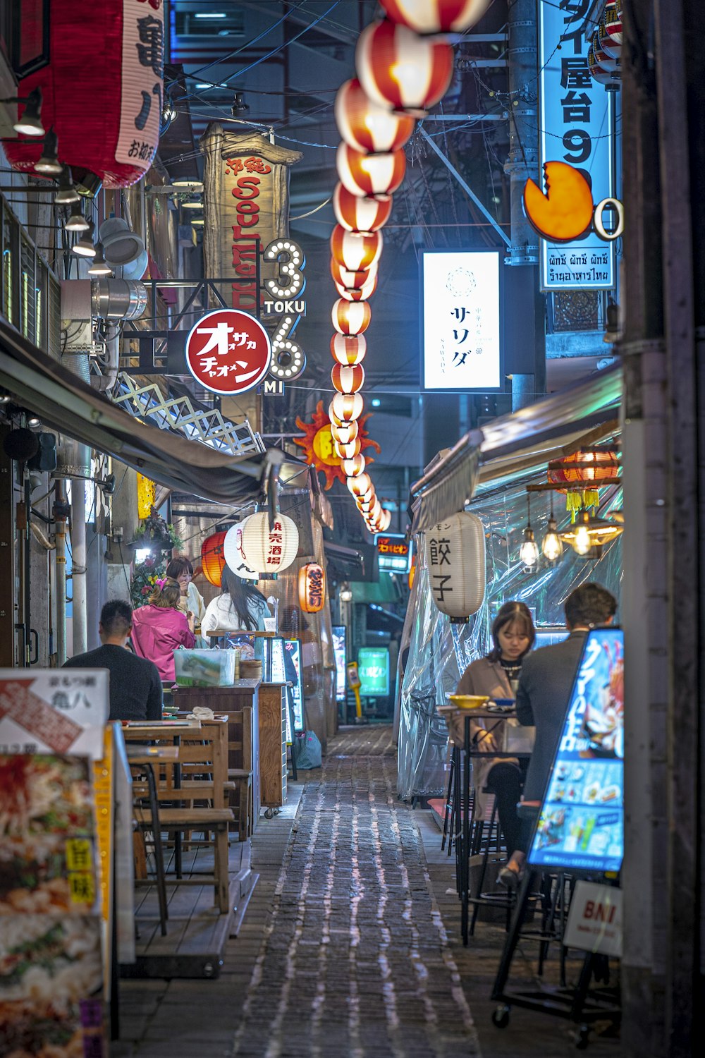 a narrow alley way with people sitting at tables
