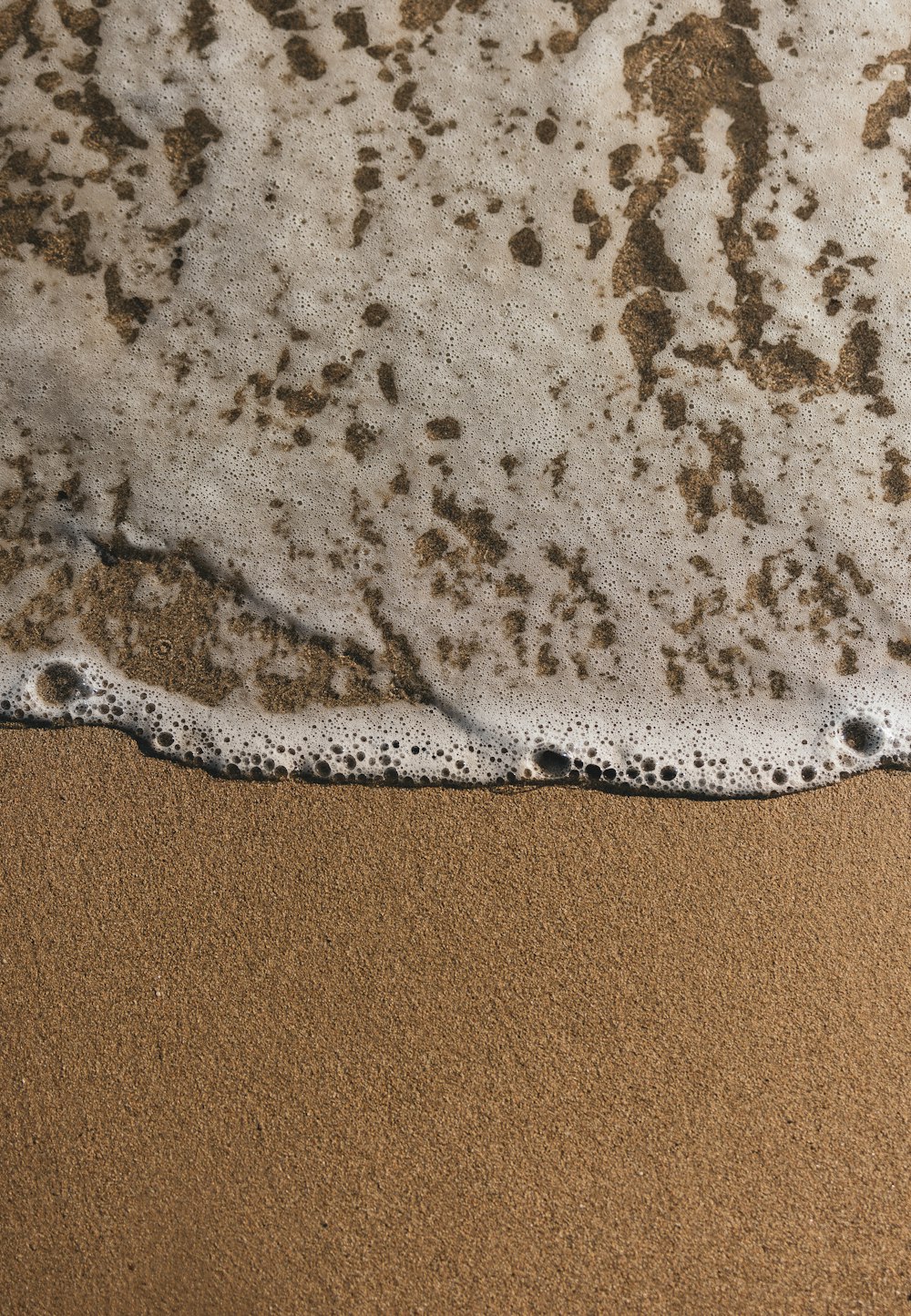 a close up of a wave on a sandy beach