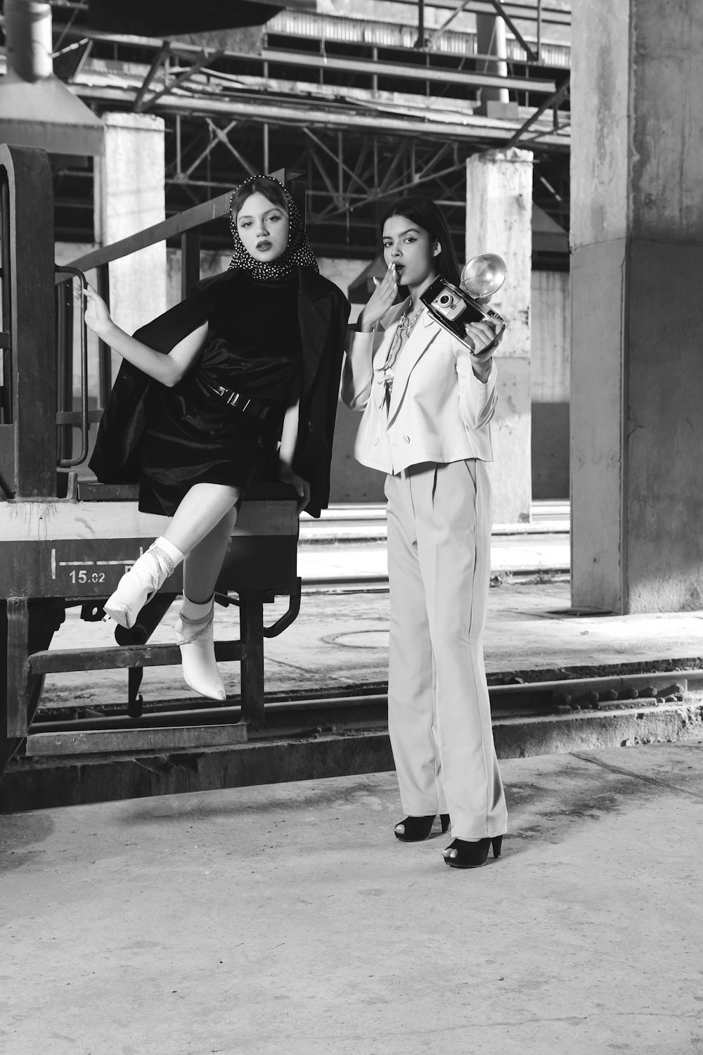 a black and white photo of two women in front of a train