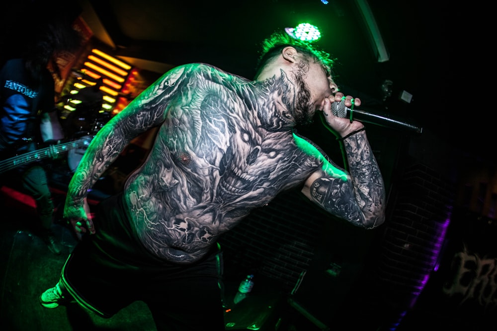 a man with tattoos on his body holding a microphone
