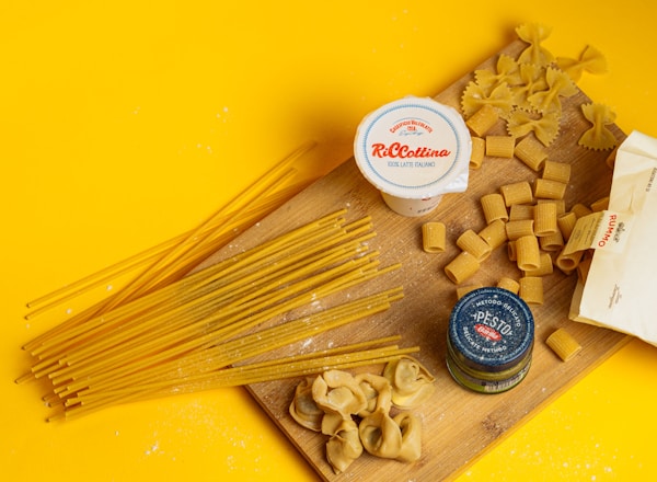 A wooden cutting board topped with lots of pasta