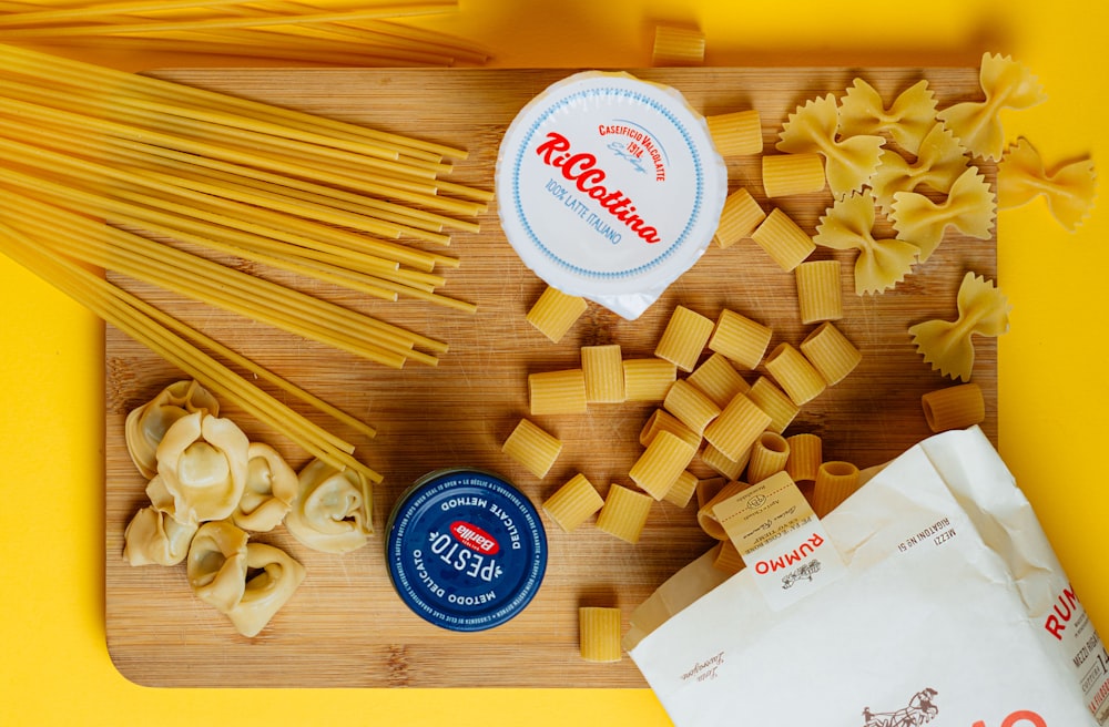 a wooden cutting board topped with pasta and cheese