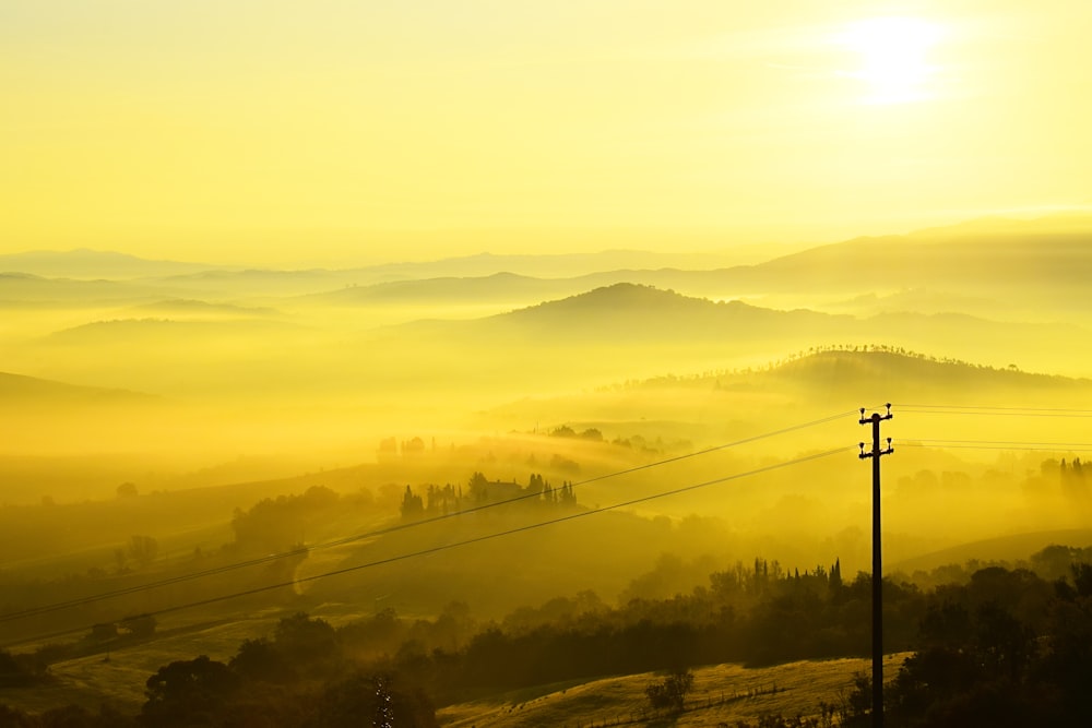 the sun is setting over a foggy valley