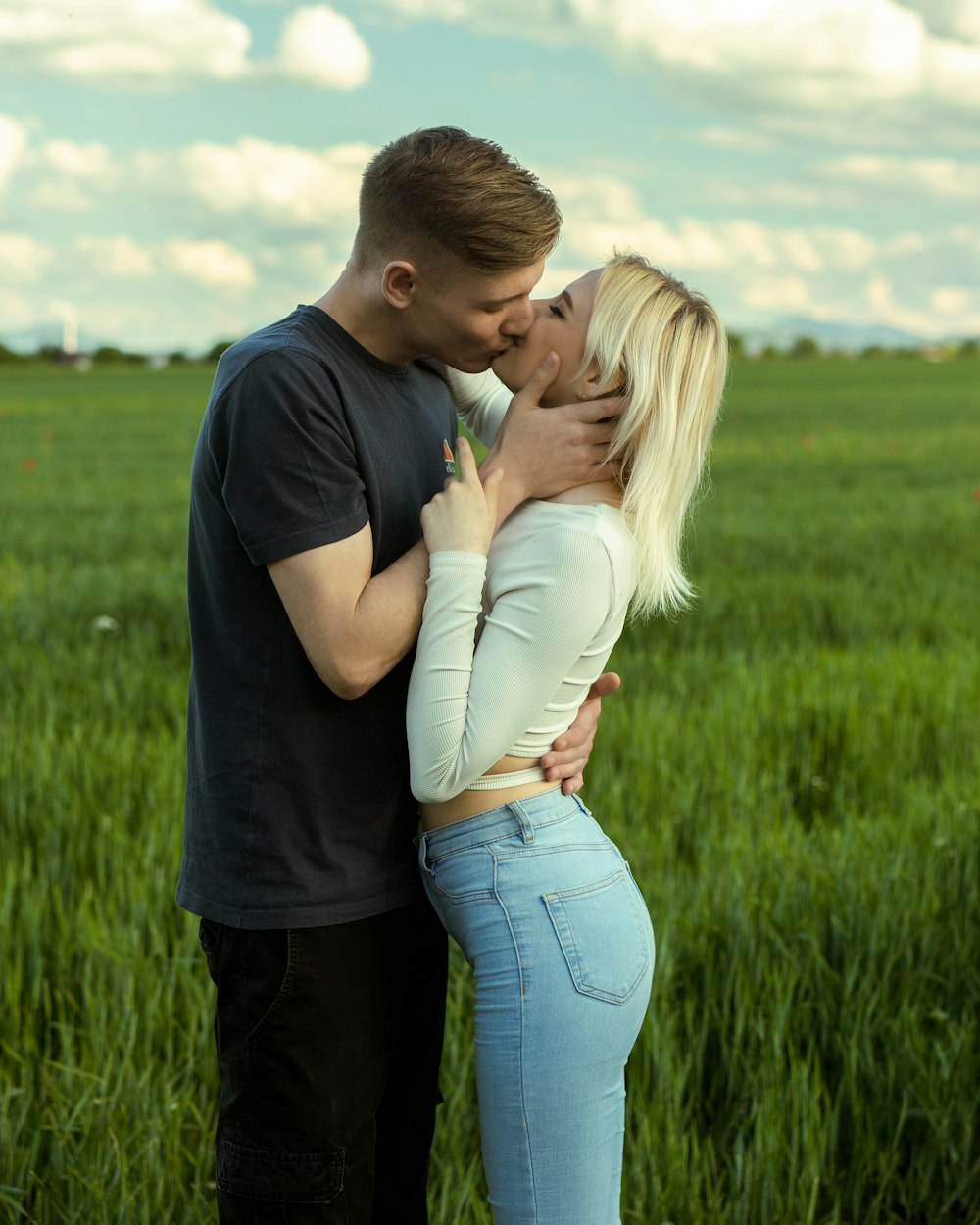 a man and a woman kissing in a field