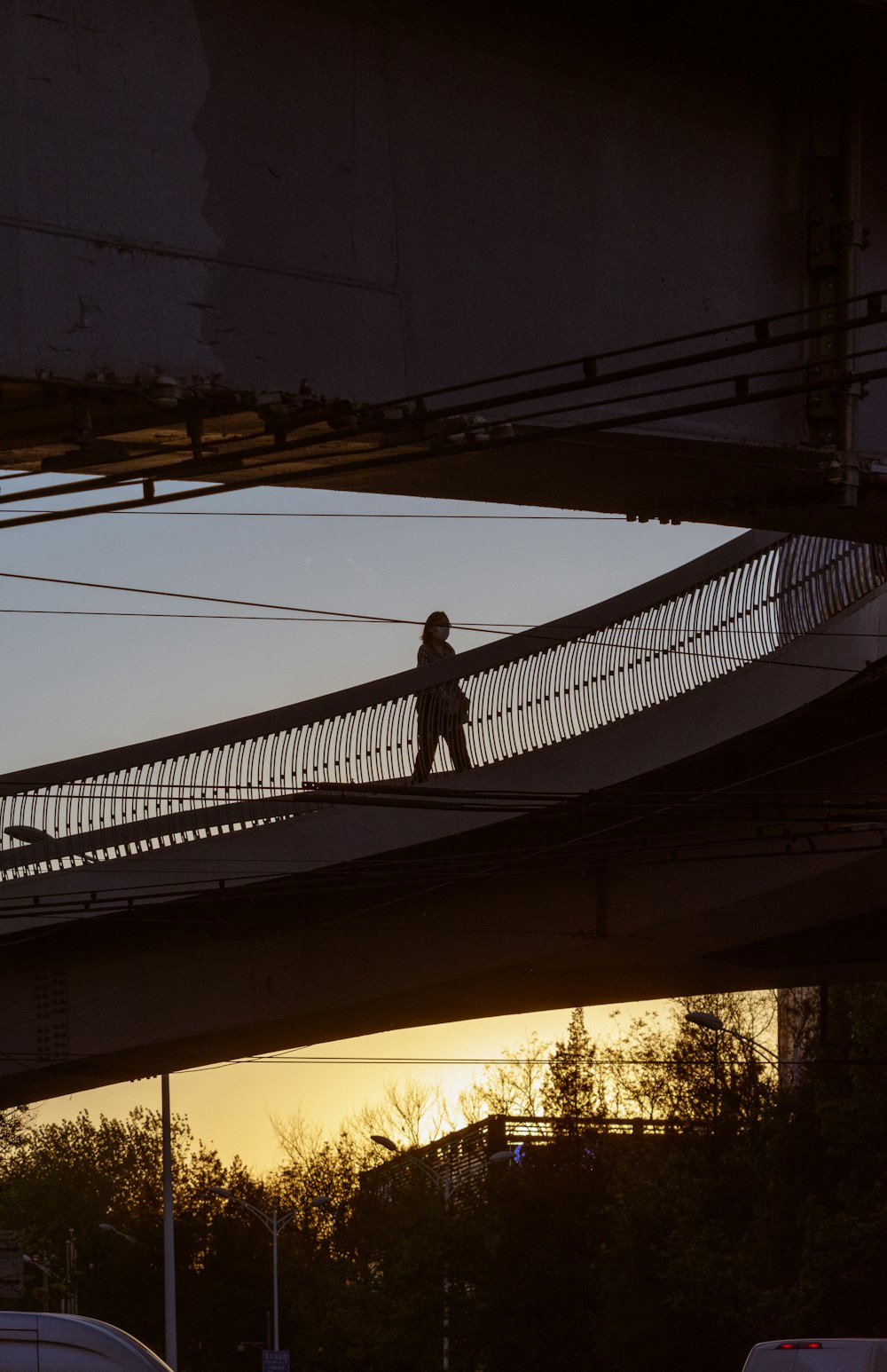 a person walking across a bridge at sunset