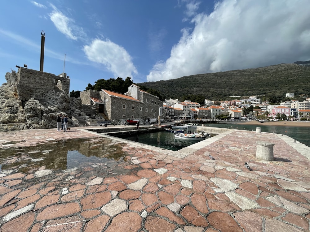 a cobblestone walkway leading to a small harbor