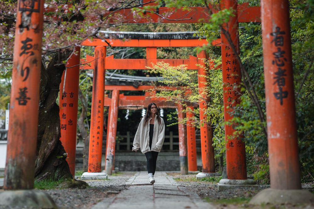 a woman standing under an orange tori 