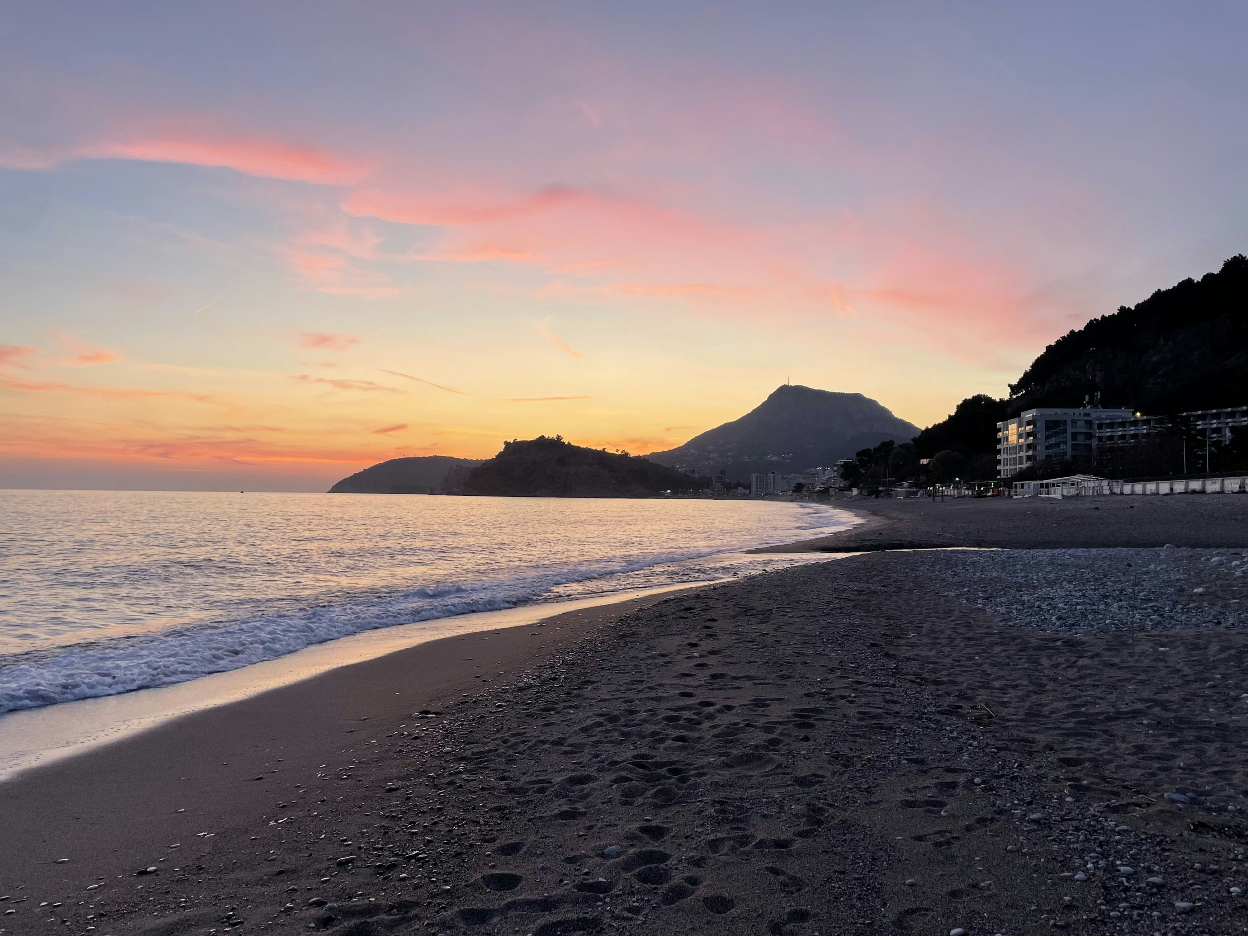 a beach at sunset with footprints in the sand