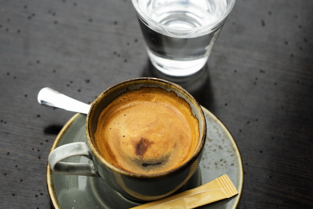 a cup of coffee on a saucer next to a glass of water