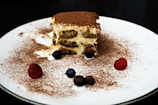 Close-up of a freshly made tiramisu in a glass cup with dusted cocoa on top.