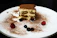 Close-up of a single elegant tiramisu slice with delicate cocoa dusting on a dark plate.
