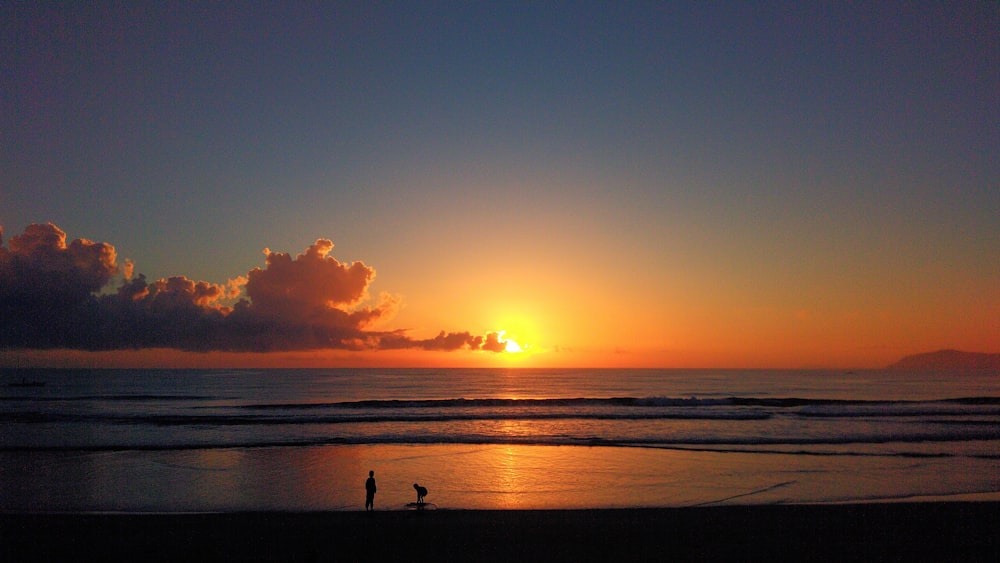 a couple of people standing on top of a beach