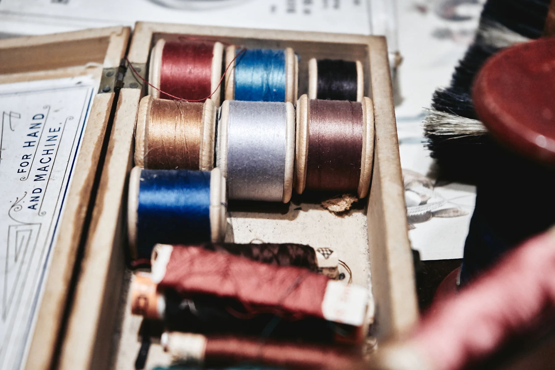 Une boîte remplie de nombreuses bobines de fil de différentes couleurs, vue du dessus