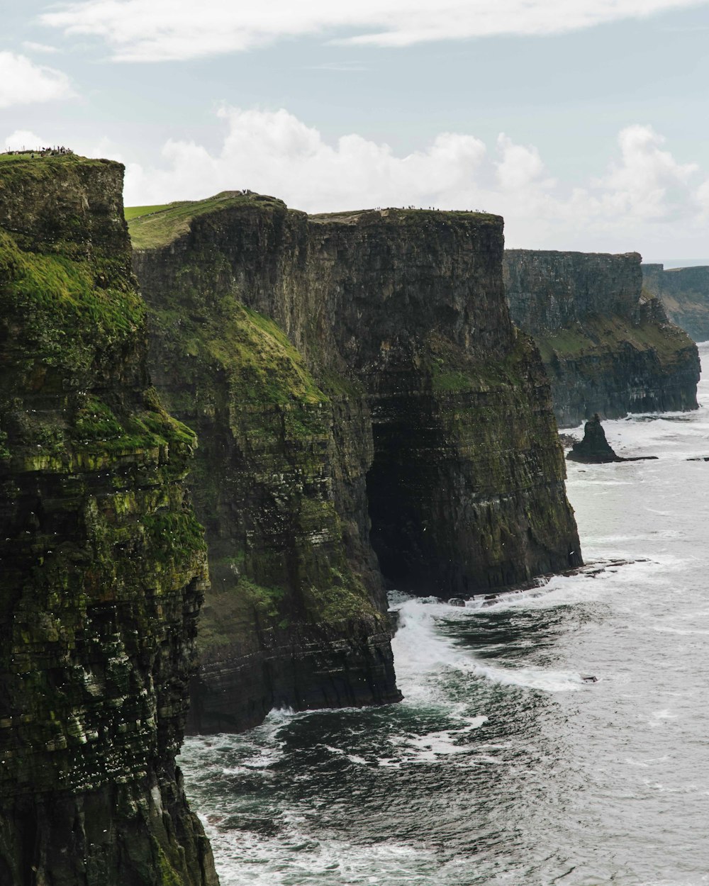 a rocky cliff with a body of water in the foreground