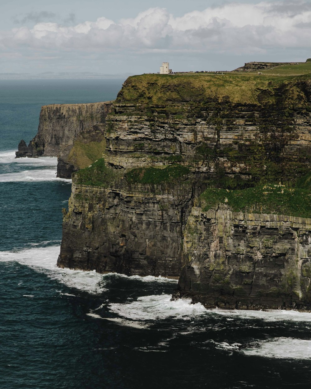 a large cliff with a lighthouse on top of it