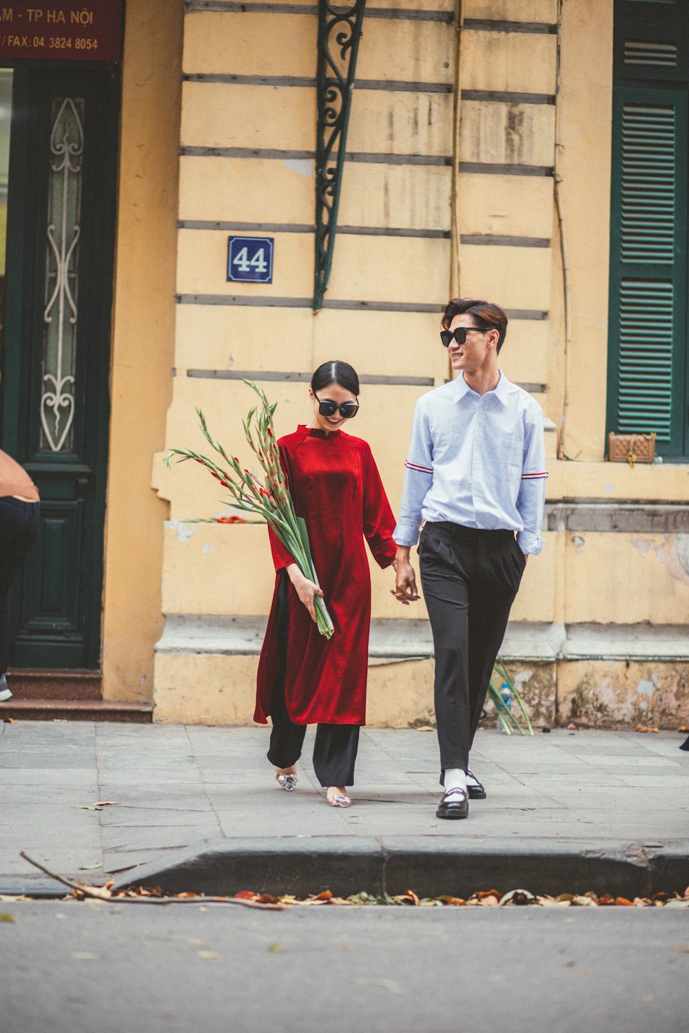 a man and a woman walking down a street holding hands