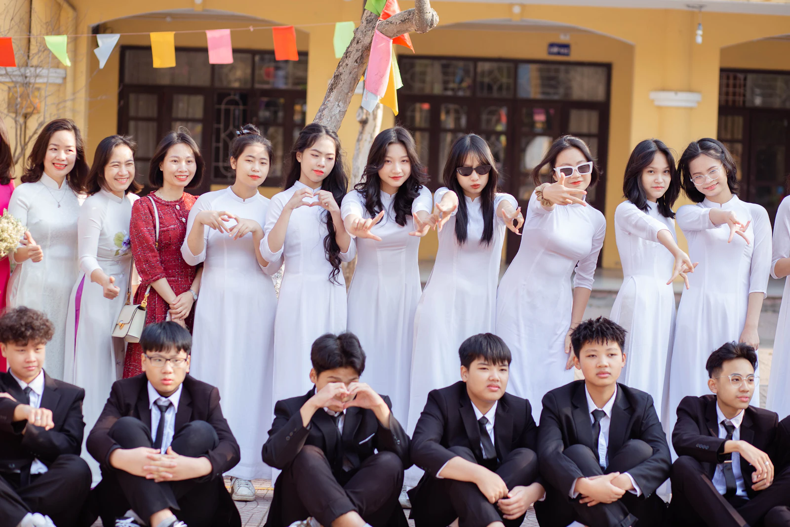 Học sinh nữ mặc áo dài trắng và học sinh nam mặc vest trước dãy lớp học trong ngày hội trường