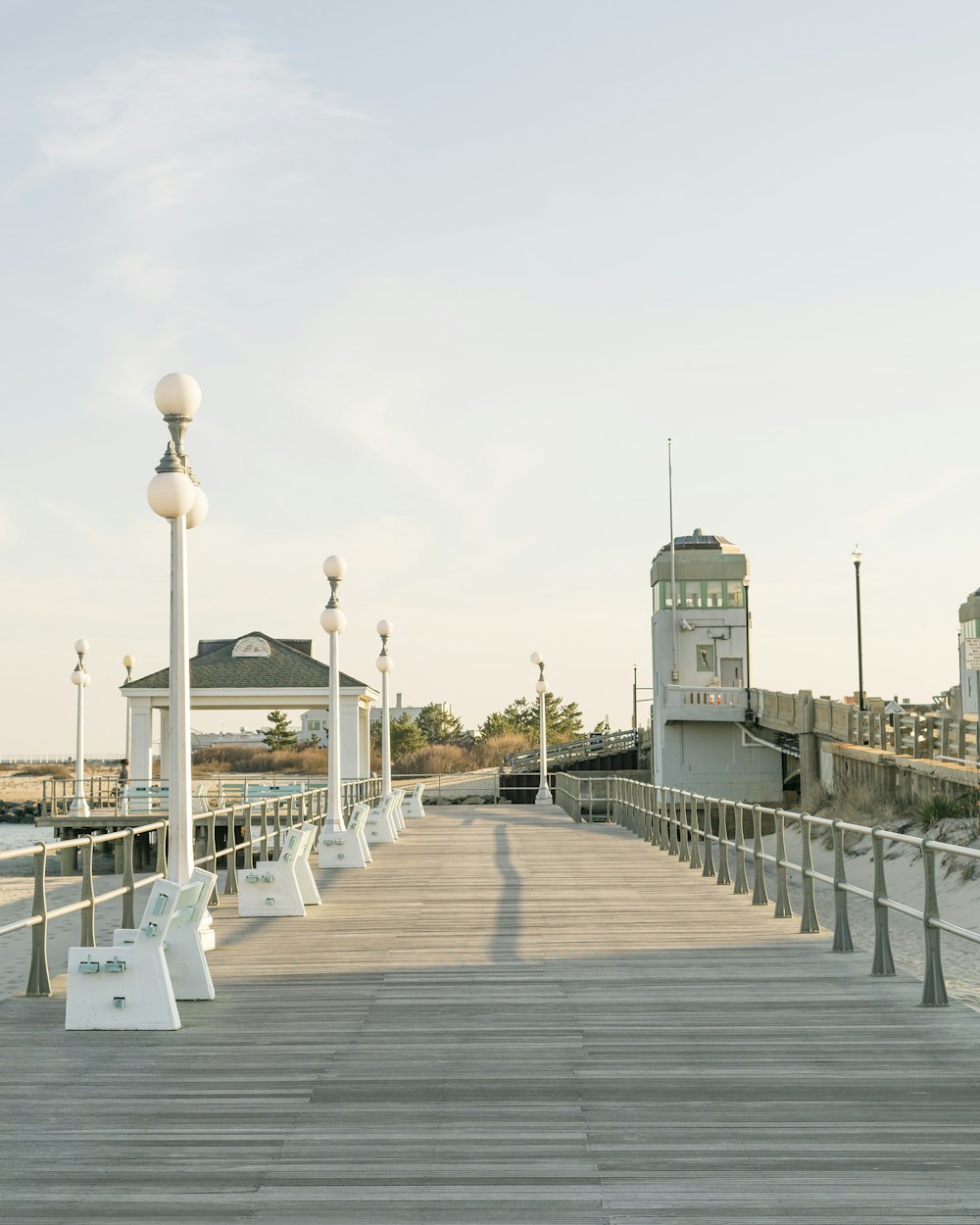 a wooden pier with benches and street lights