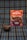 A package of 'Negrita' brand mazamorra morada flavor is placed on a plaid fabric background. In front of it, a bowl with dark purple dessert, presumably mazamorra morada, is garnished with two sticks of cinnamon.