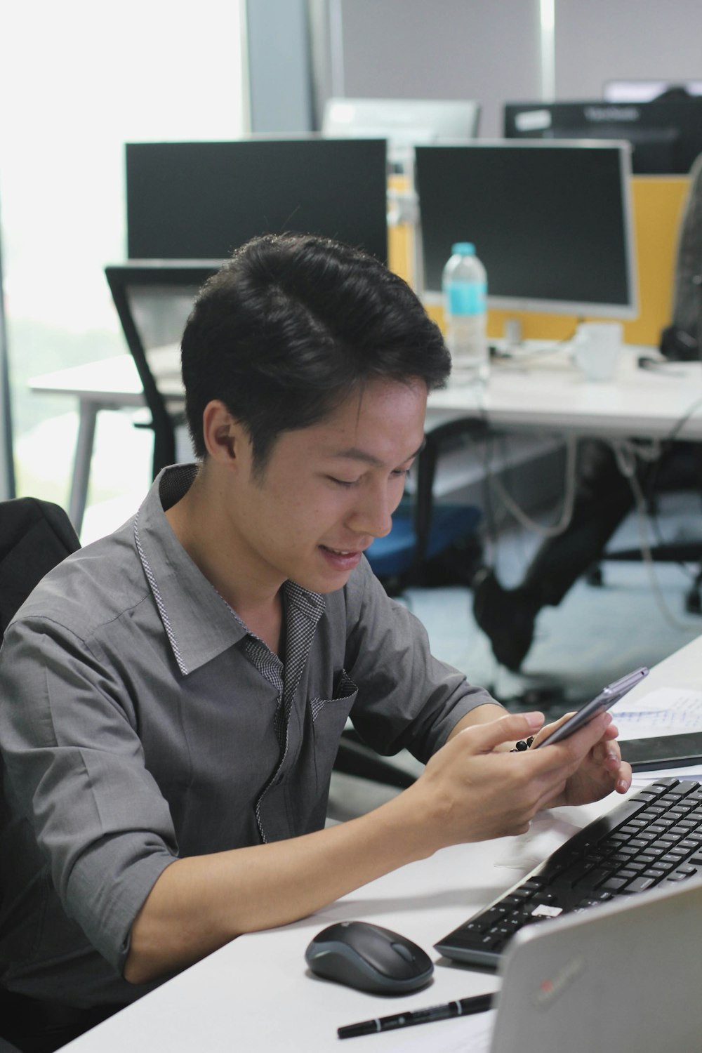 a man sitting at a desk using a cell phone