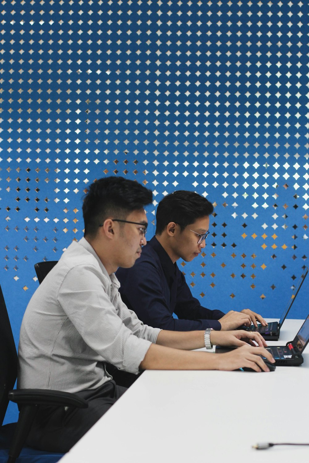 a couple of men sitting at a table with laptops