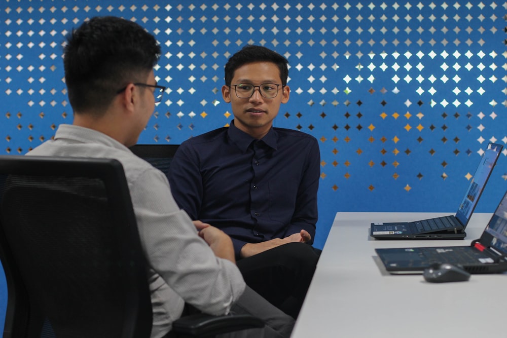 two men sitting at a table talking to each other