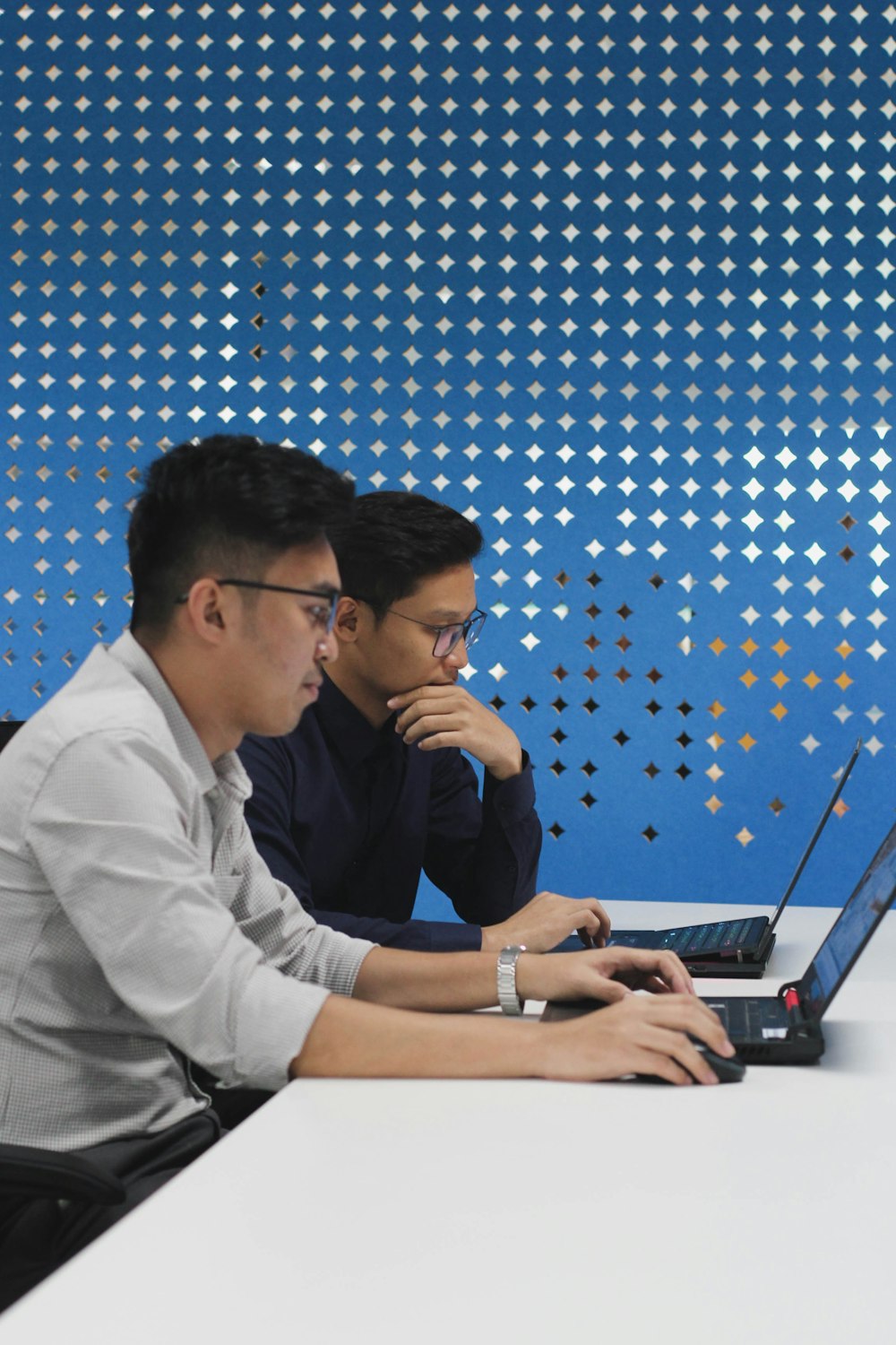 two men sitting at a table with a laptop