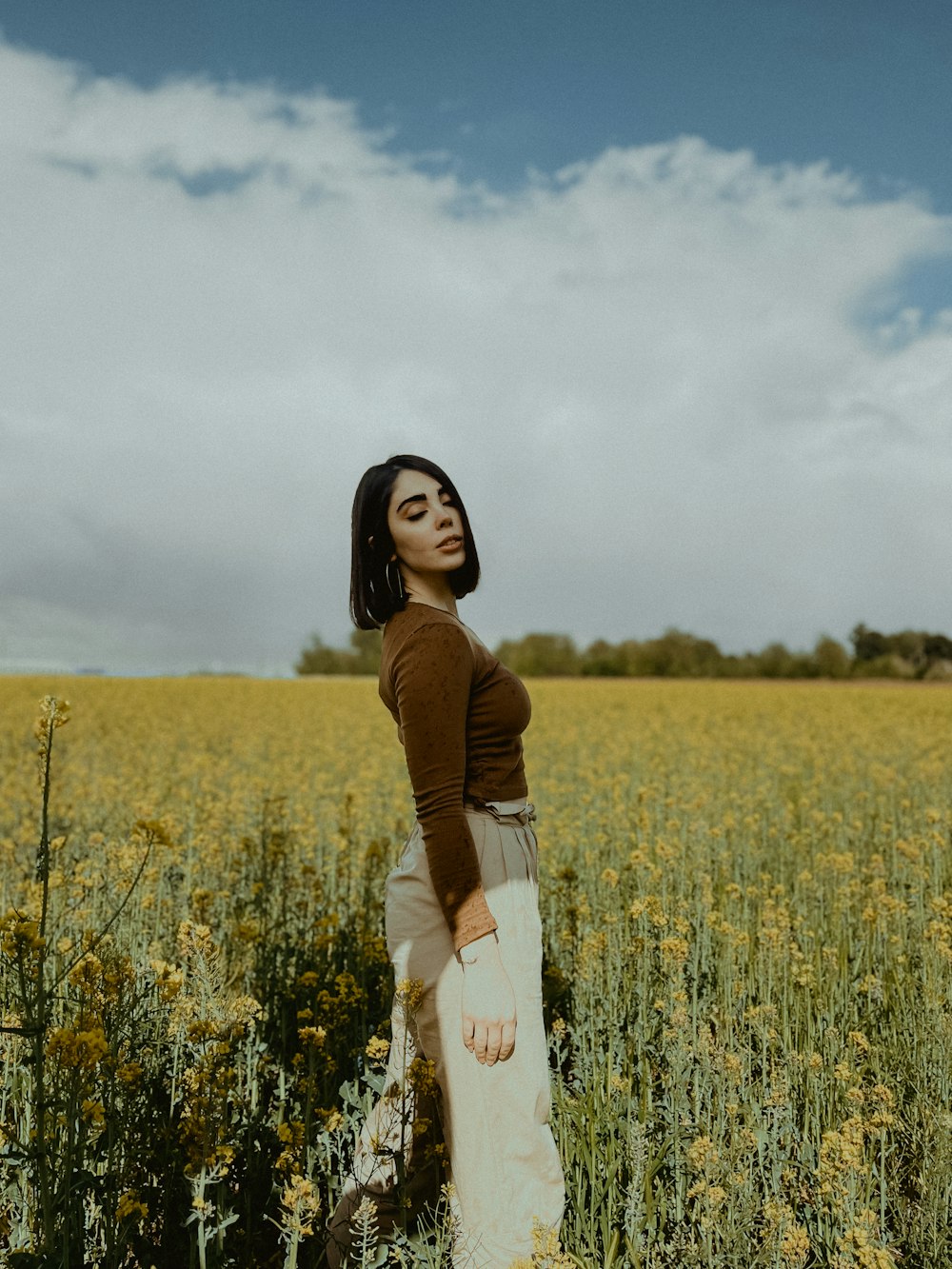 a woman standing in a field of yellow flowers