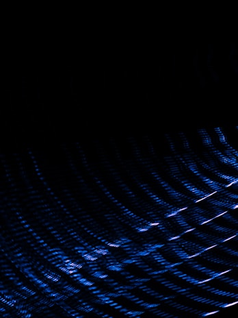 Dark background with an abstract pattern of blue light streaks creating a sense of motion and depth.