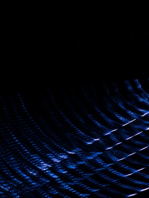 Dark background with an abstract pattern of blue light streaks creating a sense of motion and depth.