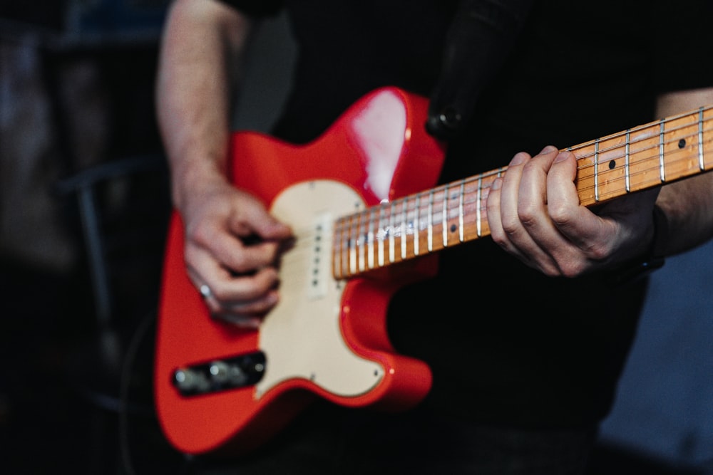 a close up of a person playing a red guitar