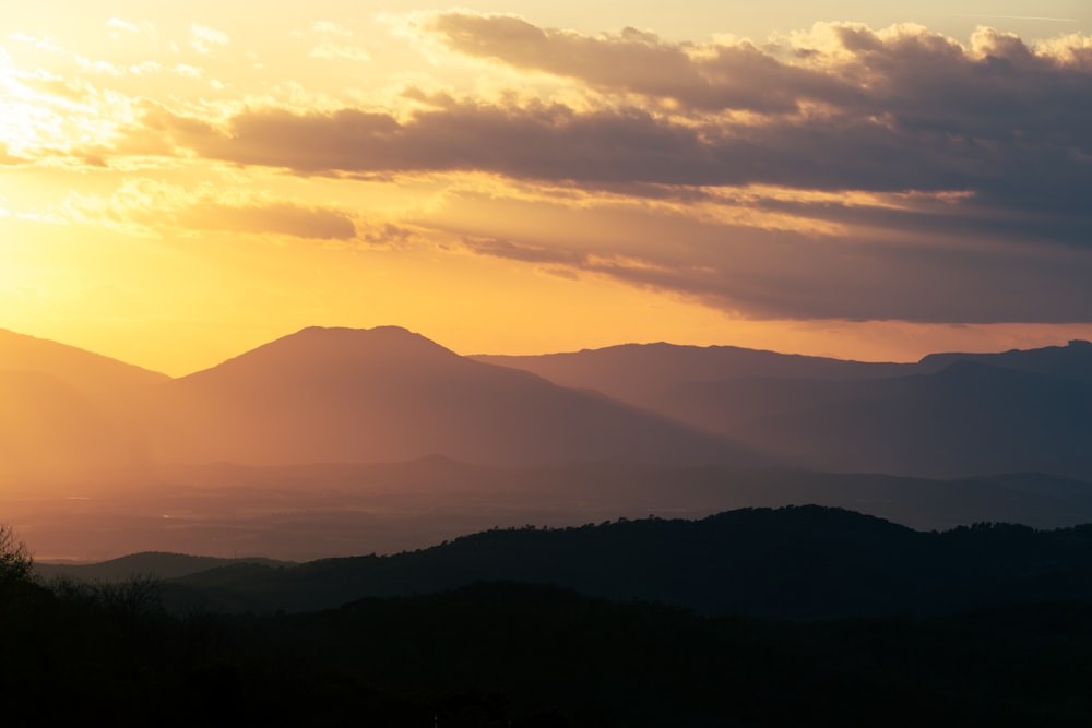 the sun is setting over a mountain range