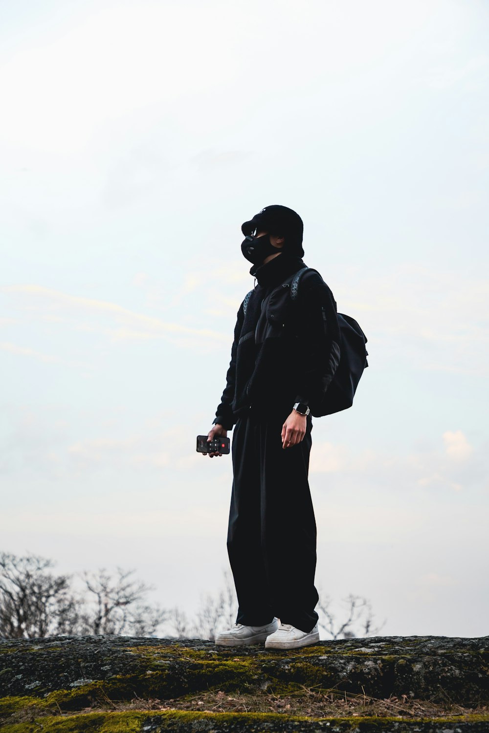 a man in a black outfit standing on top of a hill