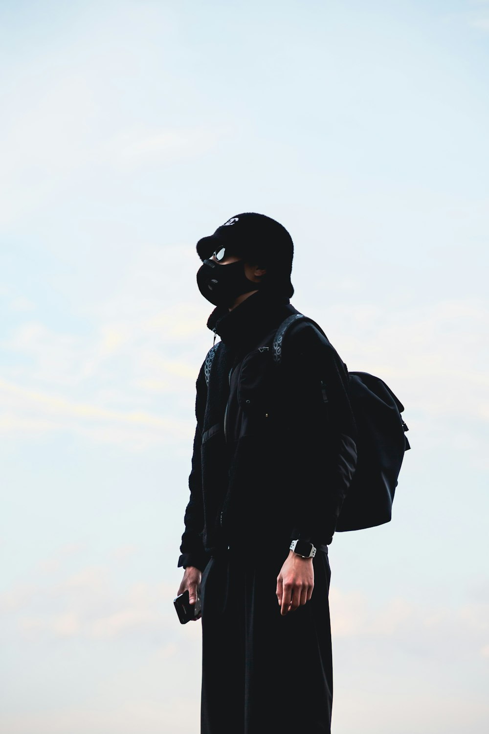 a man in a black coat and a black mask