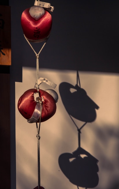 A chic black and rose gold hanging decoration casting subtle shadows against a white textured wall.