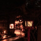 Evening exterior of the lodge lit by warm lanterns among pine trees.